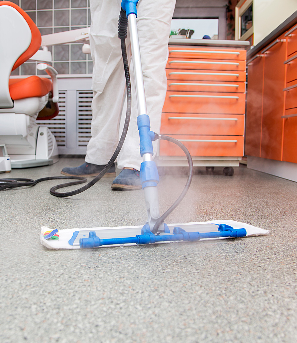 person using a floor steamer to clean hospital room